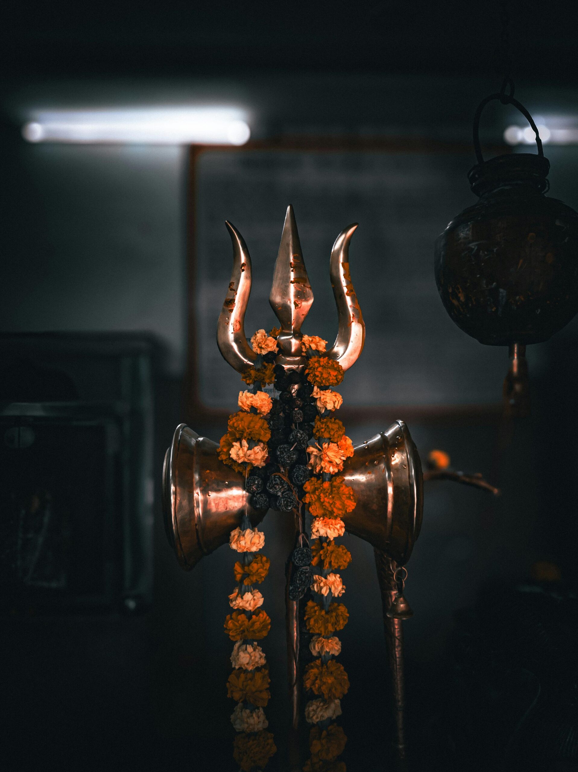 Trident symbol of Lord Shiva adorned with marigold flowers in an Indian temple.